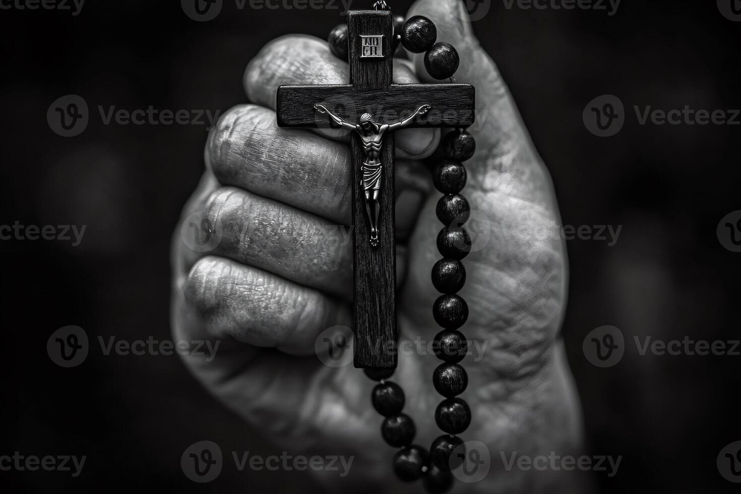 Hand holding wooden rosary with crucifix on dark background photo
