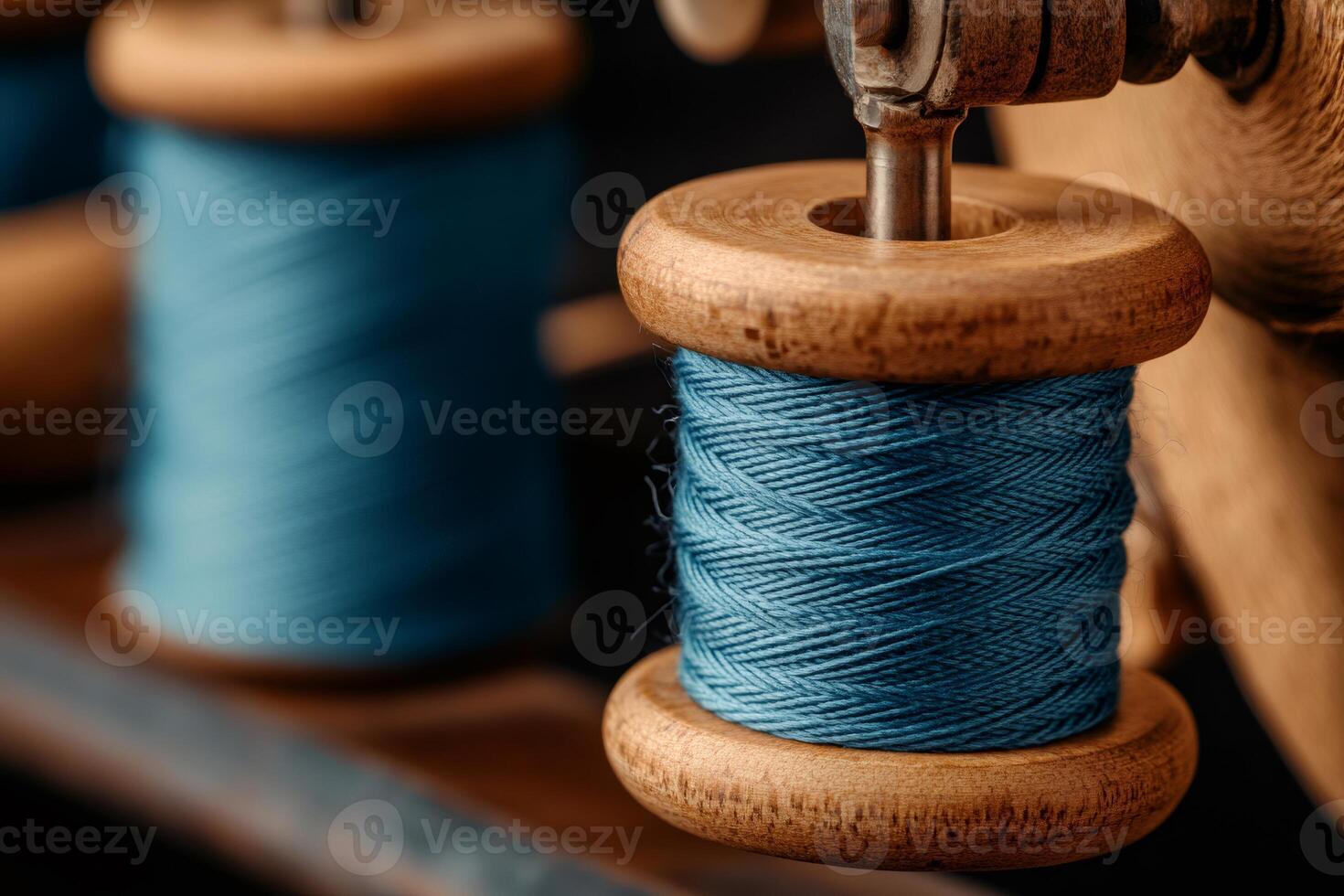Wooden spools with blue thread on an old sewing machine photo