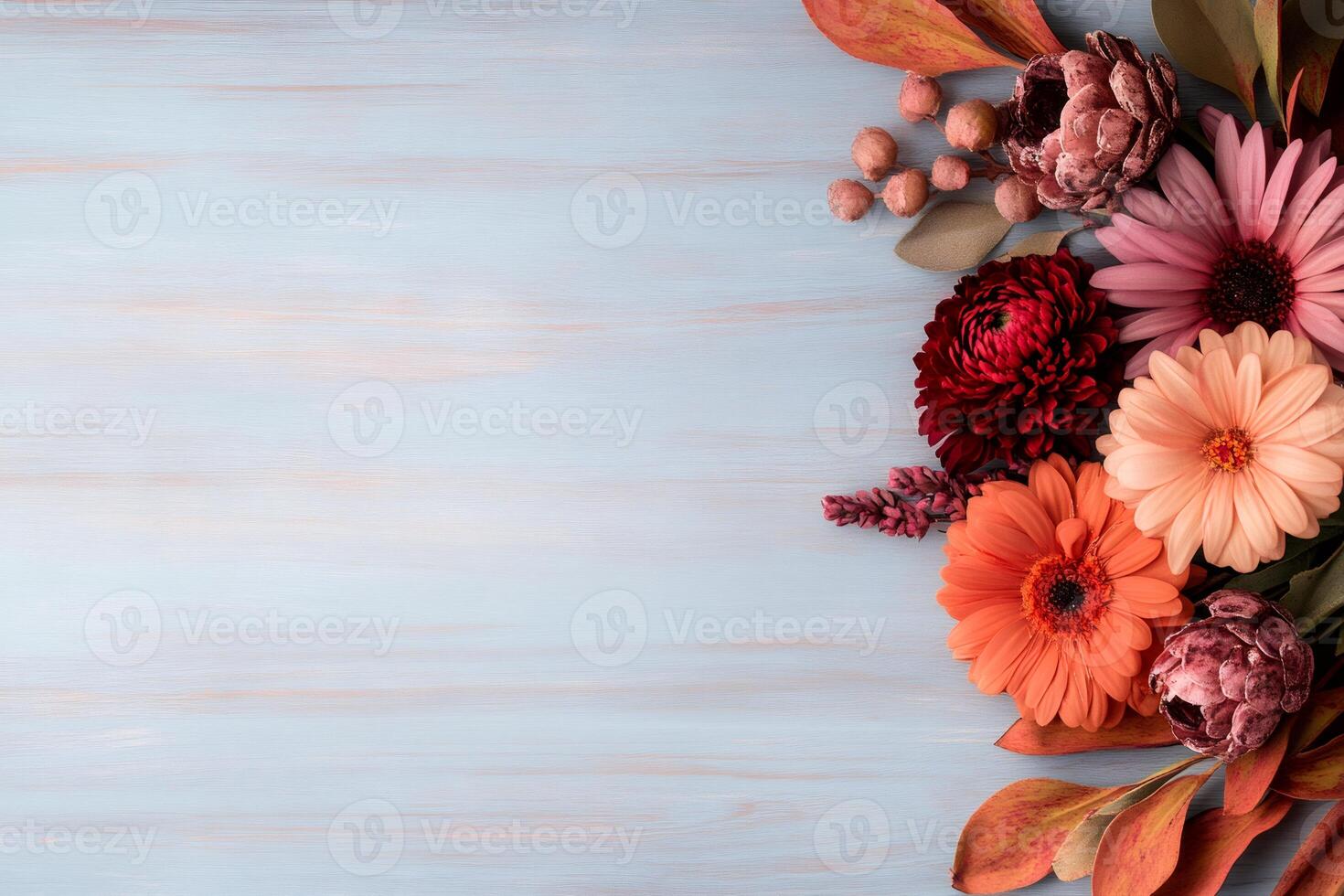 Colorful autumn flowers and leaves bordering pastel blue wooden background photo