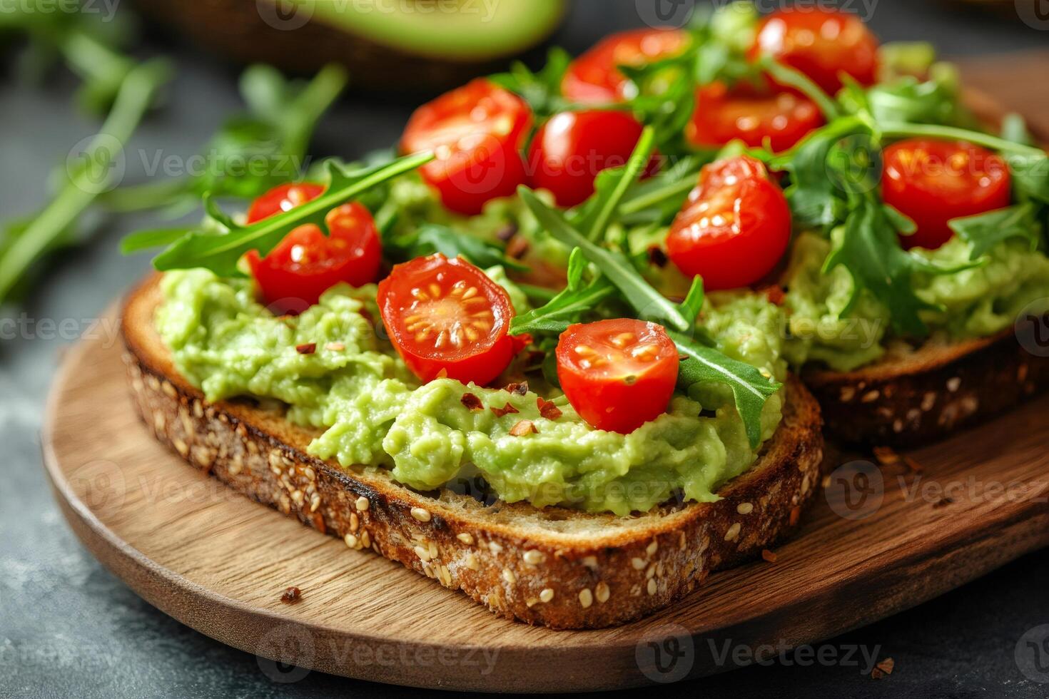 Delicious avocado toast garnished with cherry tomatoes and arugula on wooden board photo