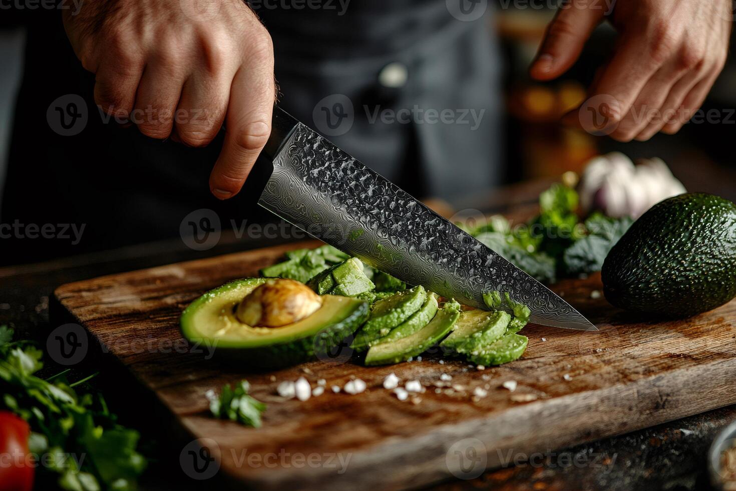 Chef slicing fresh avocado on wooden cutting board with sharp knife photo