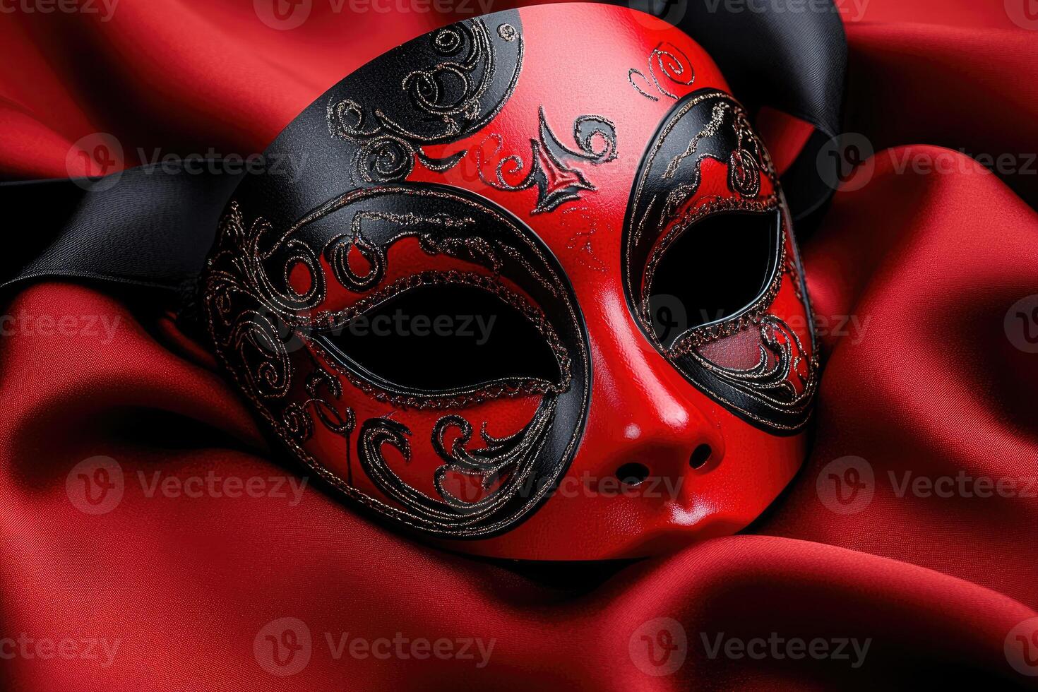 Red and black venetian mask resting on red satin photo