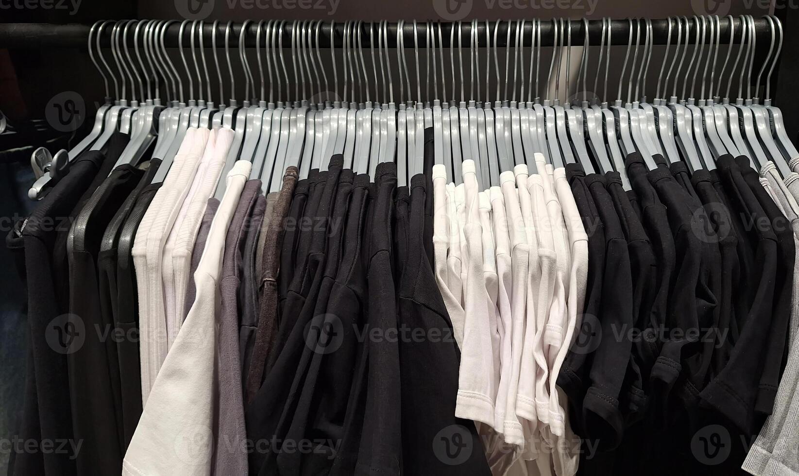 Black and white t-shirts on hangers in closet display photo