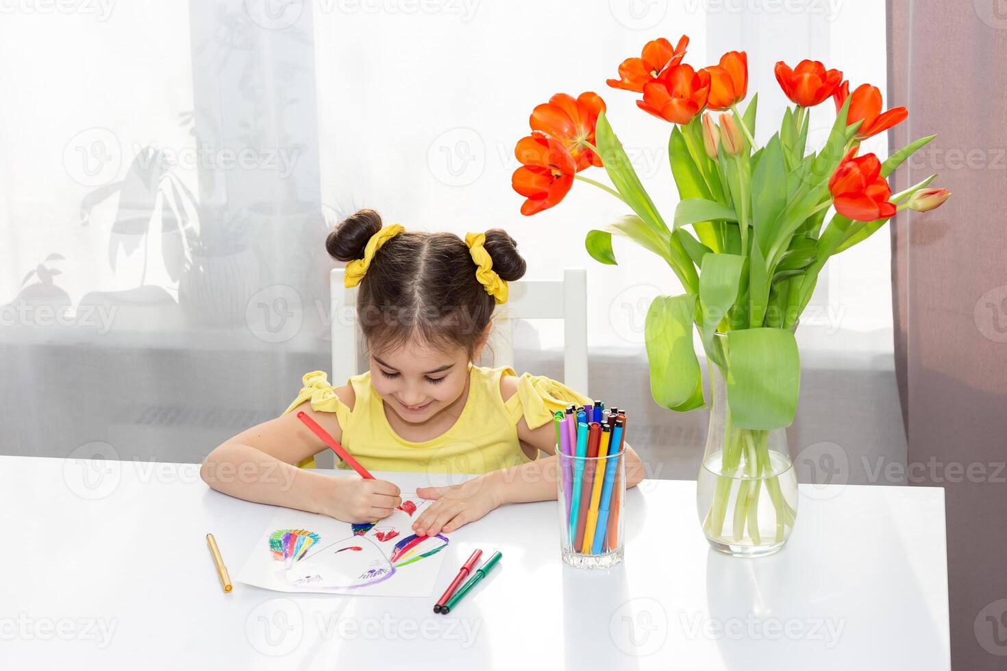Cute little brunette girl drawing with colored markers on the white table photo