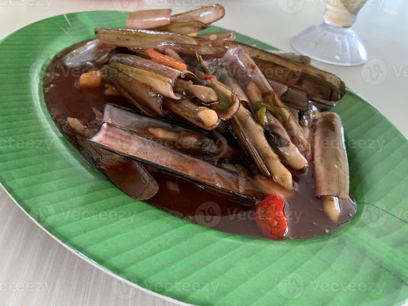 A Chinese Dish Bamboo clams steamed in sweet and sour sauce garnished with Spring Onions and Fried Garlic on green plate 5 photo