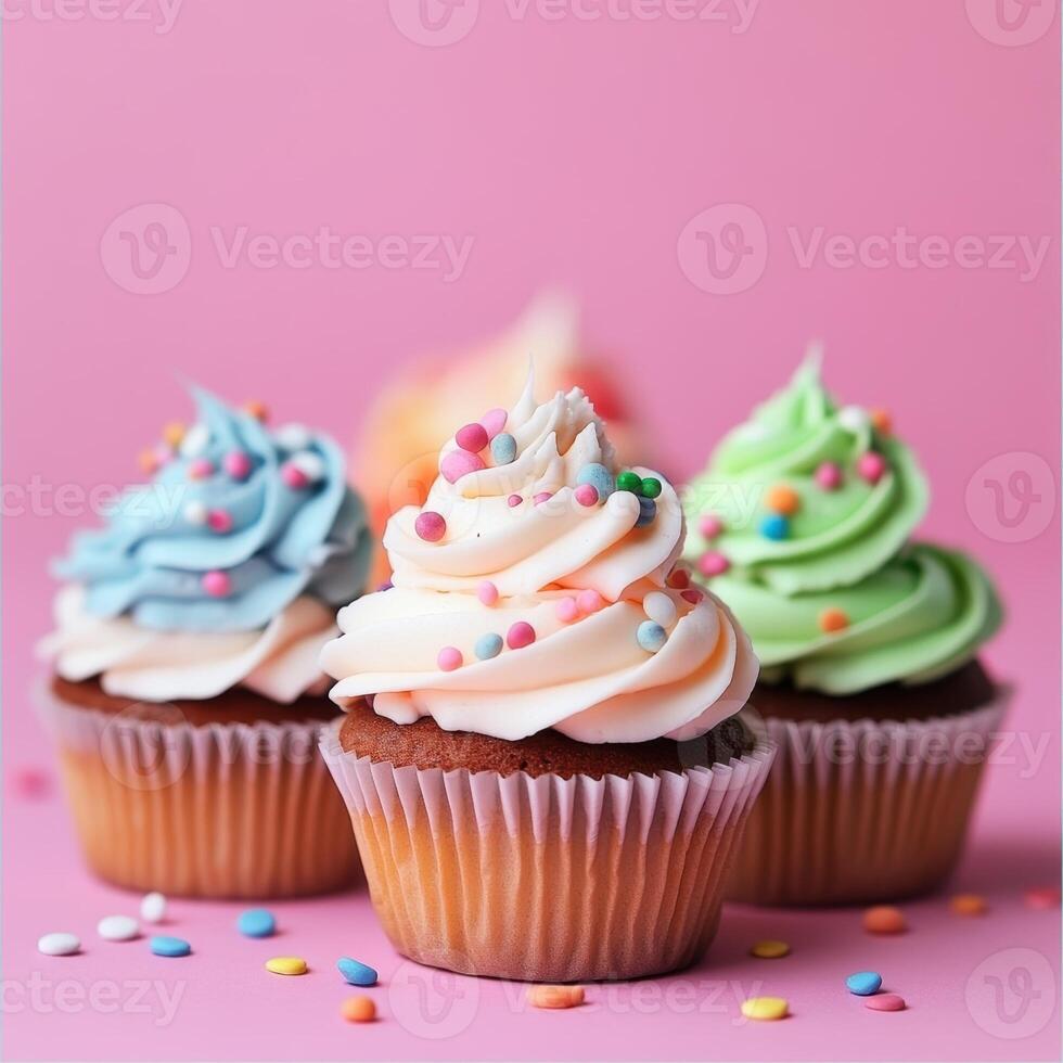 Three cupcakes with frosting on a pink background photo