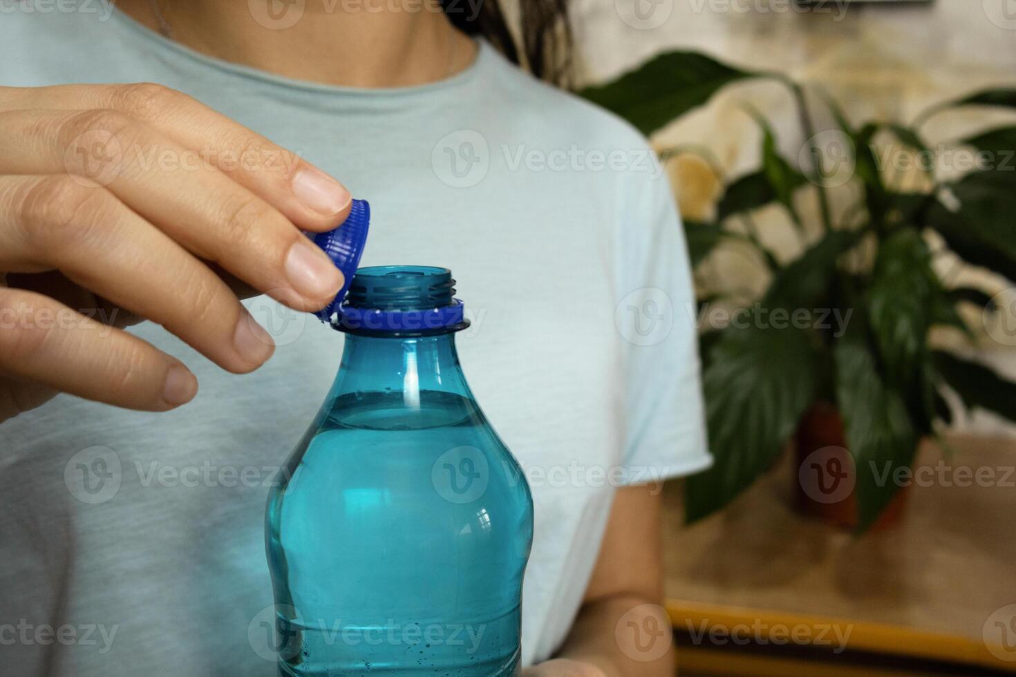 Woman hands opening bottle with stationary plastic cap. photo