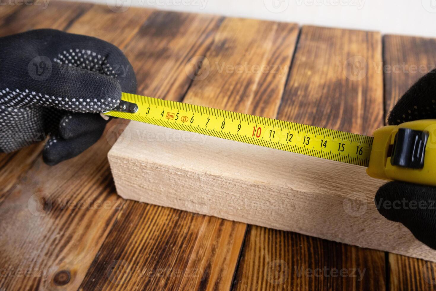 Male hands measuring piece of wood with yellow measuring tape photo