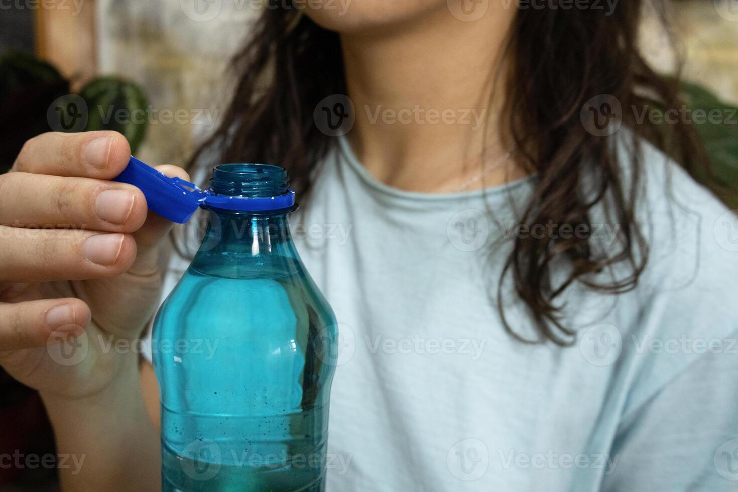 Bottle with stationary plastic cap in woman hand. The new design means the cap remains attached to the bottle after opening photo