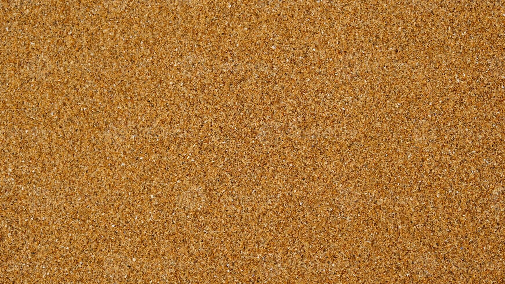 Golden sand background with fine texture of desert or beach. Granules small and tightly packed, uniform and natural pattern. Ideal for yellow textures, summer sun holiday concept or design elements. photo