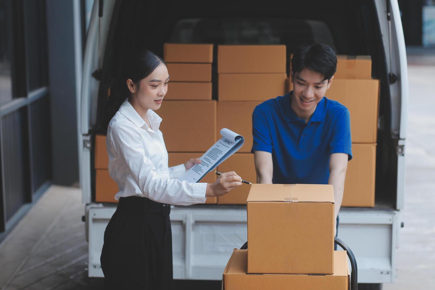 A man and woman are standing next to a truck with boxes photo