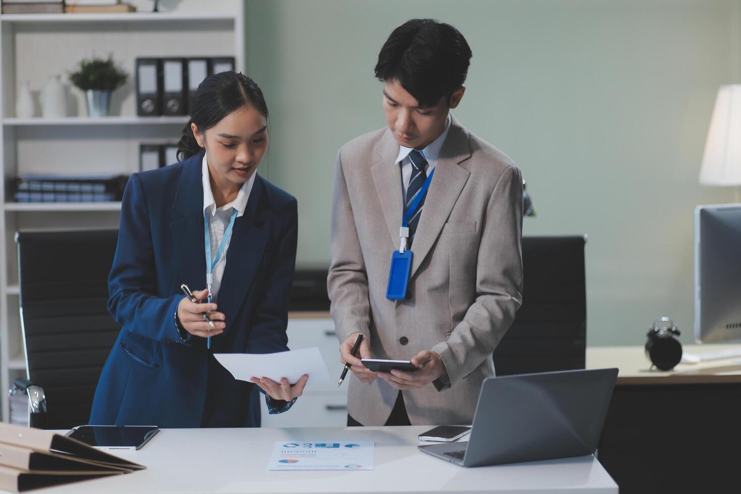 Two business people standing at a desk with a laptop photo