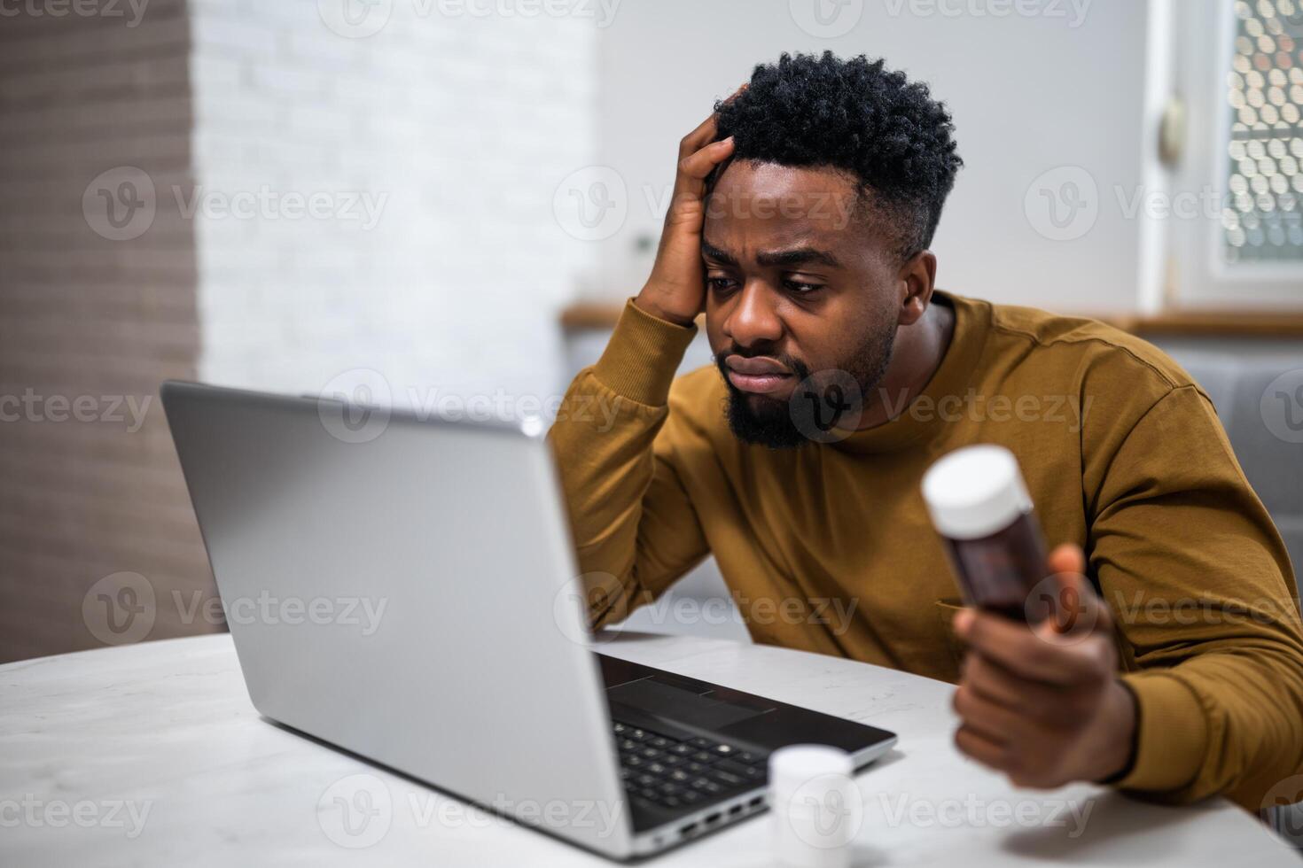 African-American man worried about his health issue, using laptop and searching for advice on Internet while sitting in his living room. photo