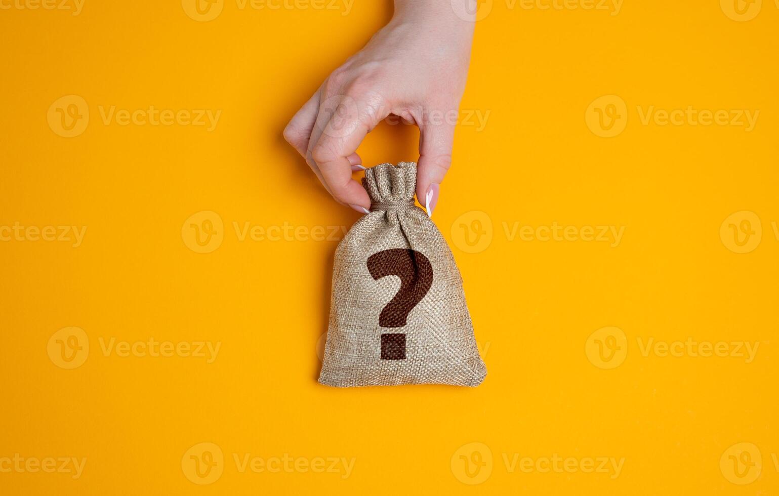 Hand holding a bag with a question mark. Financial uncertainty, hidden wealth, or unknown investment outcomes. Risky ventures, surprise rewards, or the unpredictability of economic decisions. photo