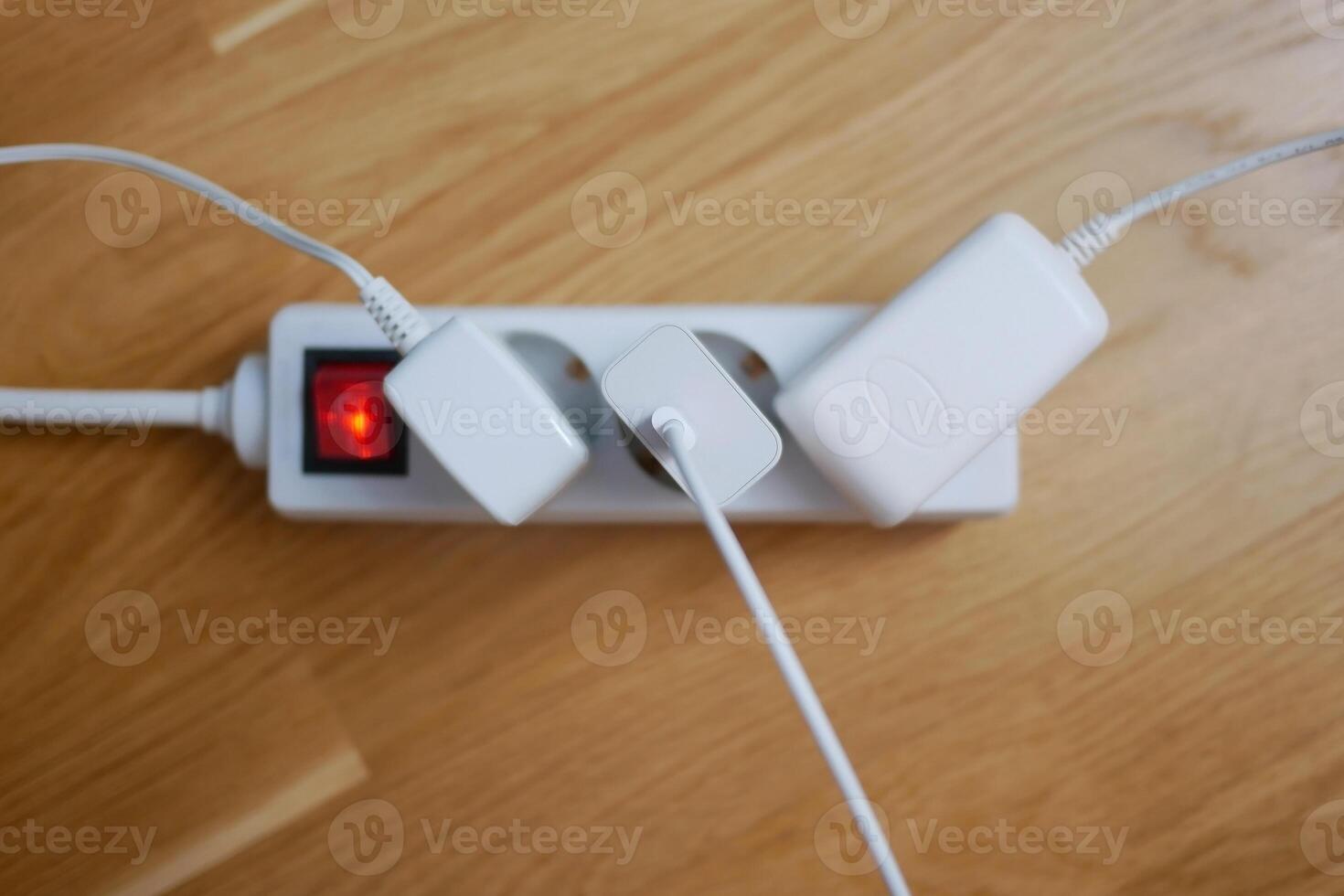 Three electric cables are plugged into a power strip extension cord photo