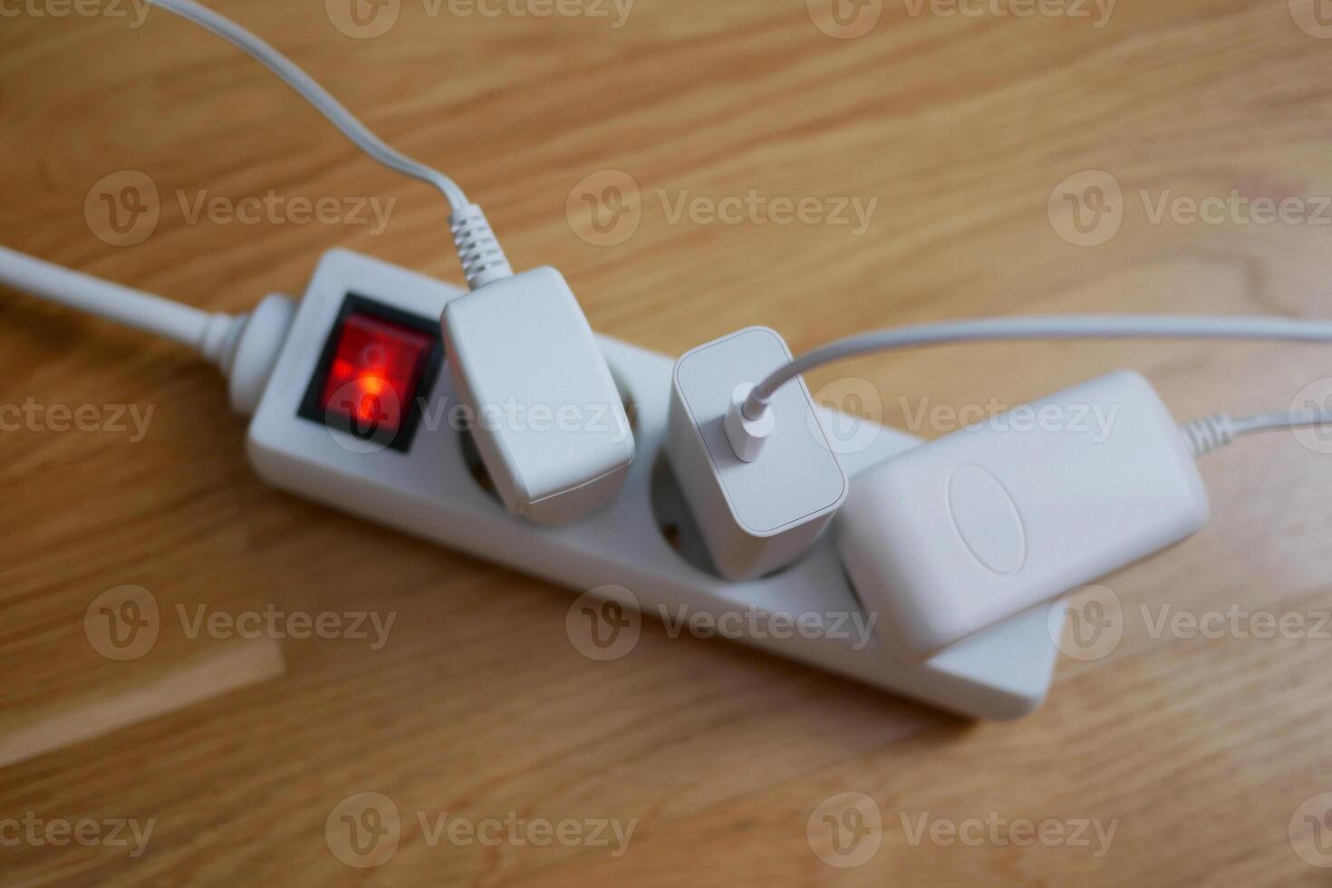 Three electric cables are plugged in power strip socket extension cord photo
