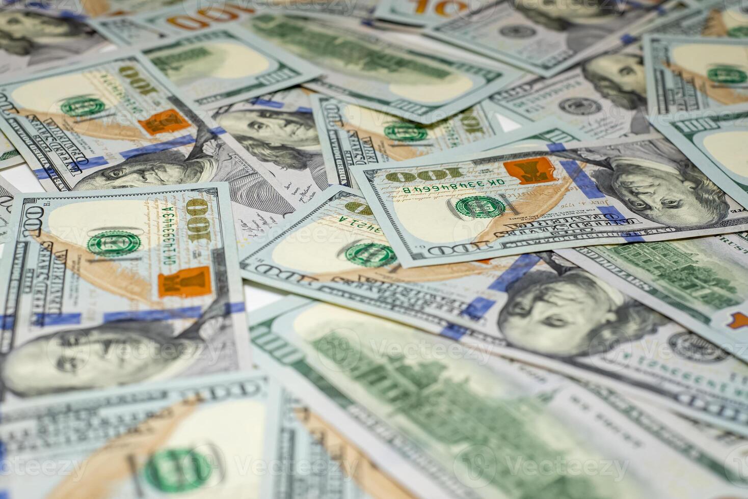 Stacks of hundred-dollar bills are spread out on a surface emphasizing the details of the new currency design side view photo