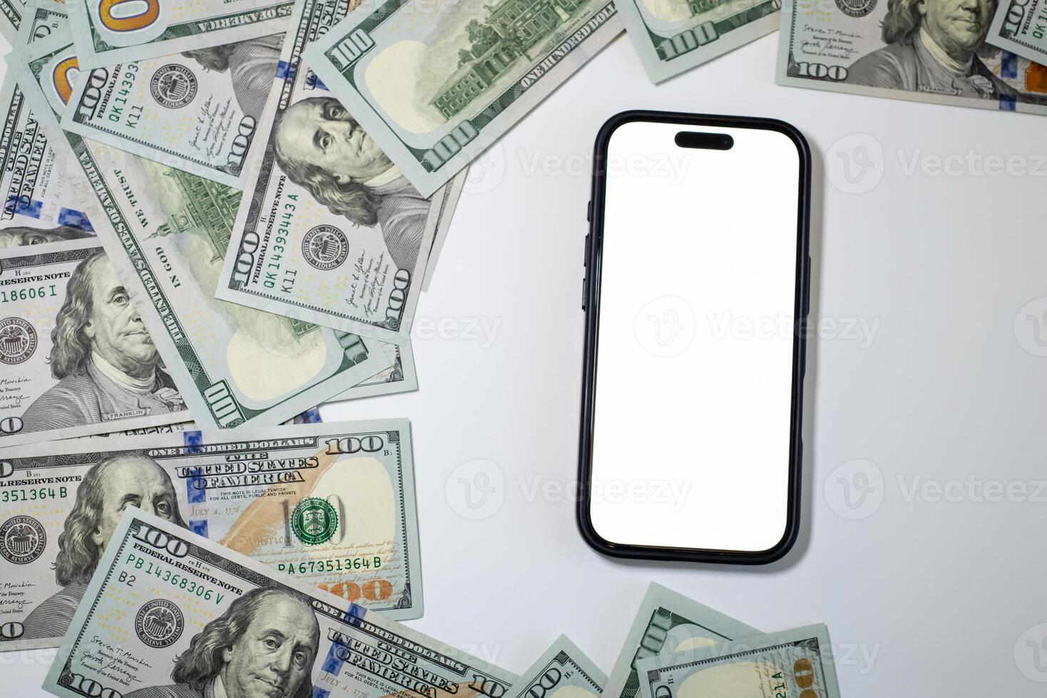Currency, dolar bills spread out on a white background, in the center a phone with a white screen. Composition for business, marketing, bank photo
