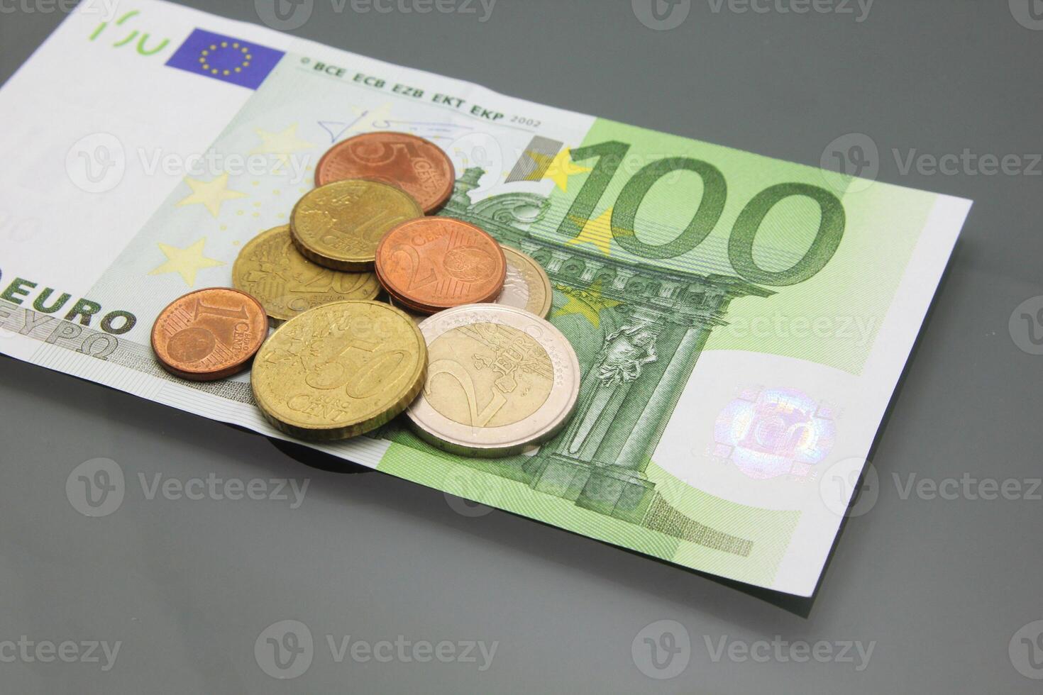 Hundred euro bill and coins on a dark background photo
