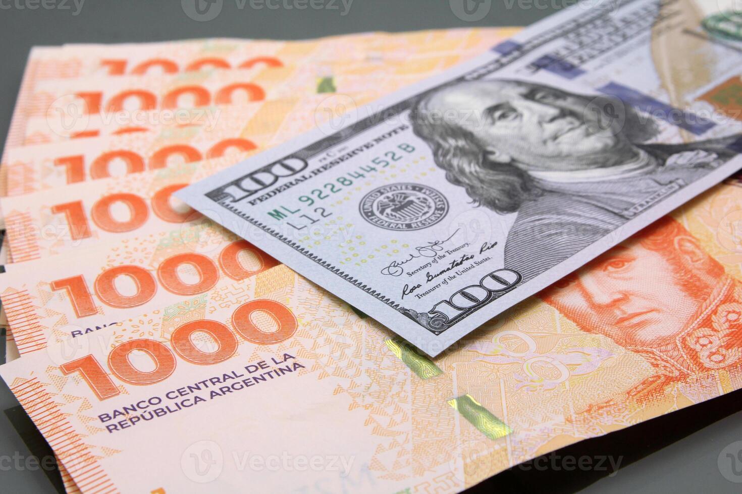 Argentine Pesos Banknotes Stack with One Hundred Dollar Bill on Top photo
