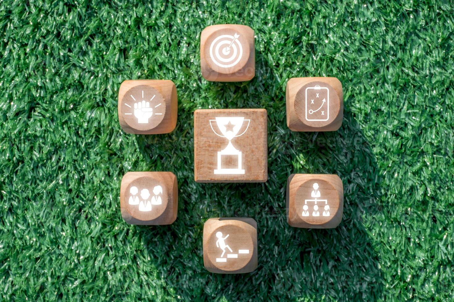 Wooden blocks with achievement icons on grass, representing success, goals, and teamwork. photo