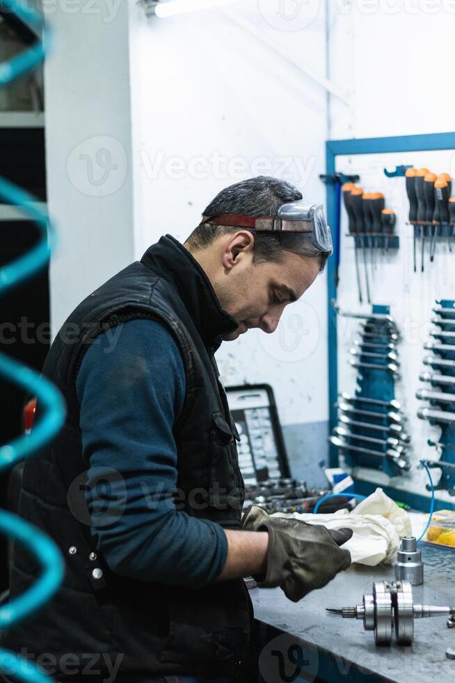 Professional mechanic using spanner while assembling vehicle. engine details at workbench photo