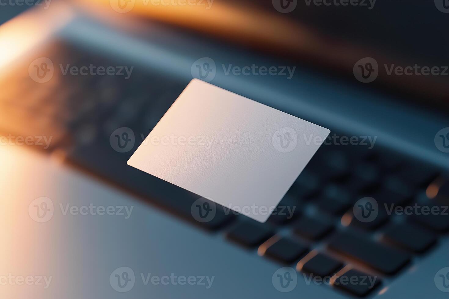 A blank business card hovers slightly above a laptop keyboard, beautifully illuminated by soft lighting. The modern workspace in the background exudes innovation and tech appeal photo