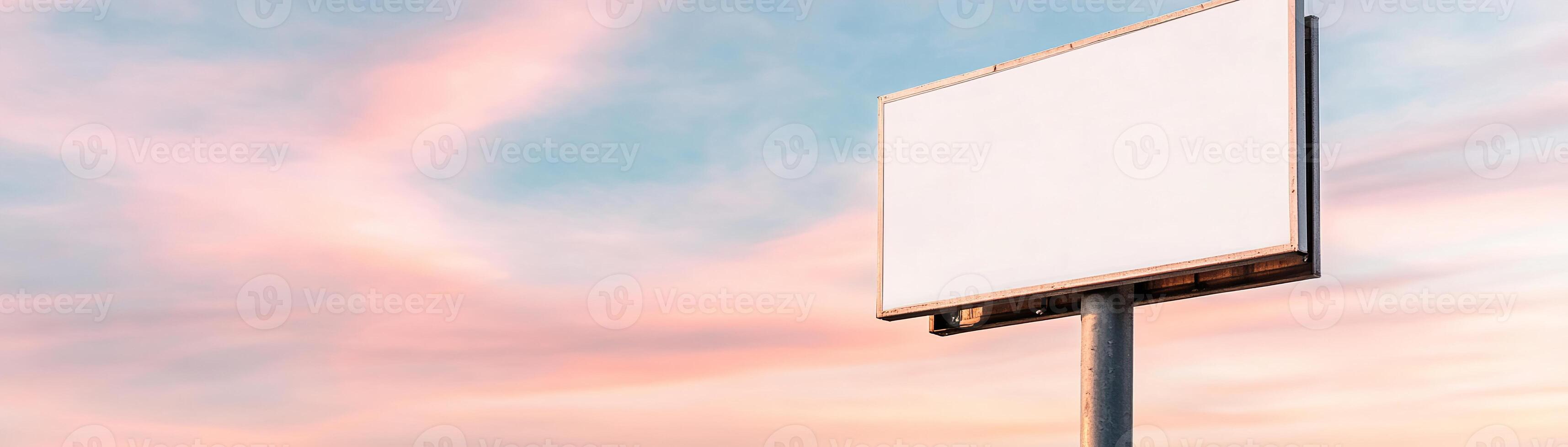A large blank signboard is mounted on a sturdy metal pole beside a wide highway, with moving vehicles in the background and an open landscape under a partly cloudy sky photo