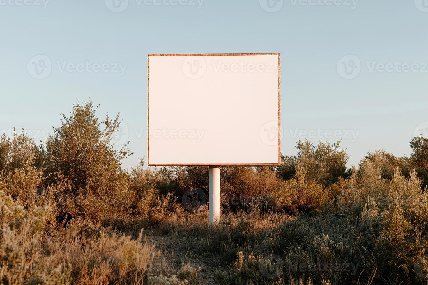 A large blank billboard stands alone on a quiet country road, with expansive green fields and a vibrant blue sky in the background. The peaceful setting is ideal for nature-focused brands photo