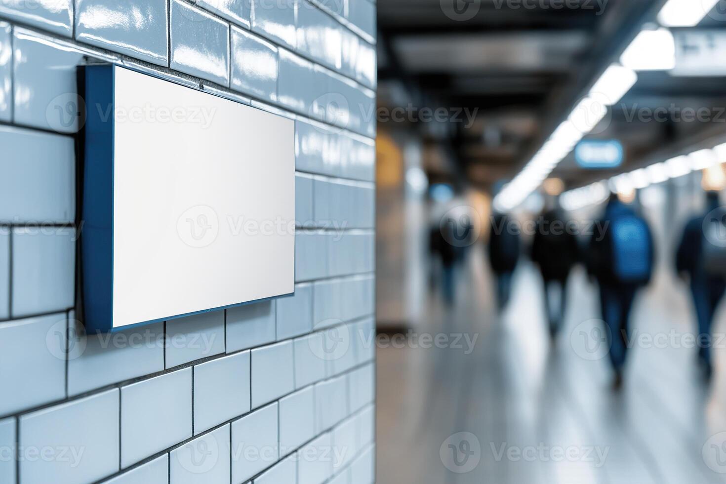 A sleek blank billboard is mounted on a tiled wall in a contemporary subway station. Softly blurred commuters pass by, enhancing the dynamic urban environment ideal for transit advertising photo