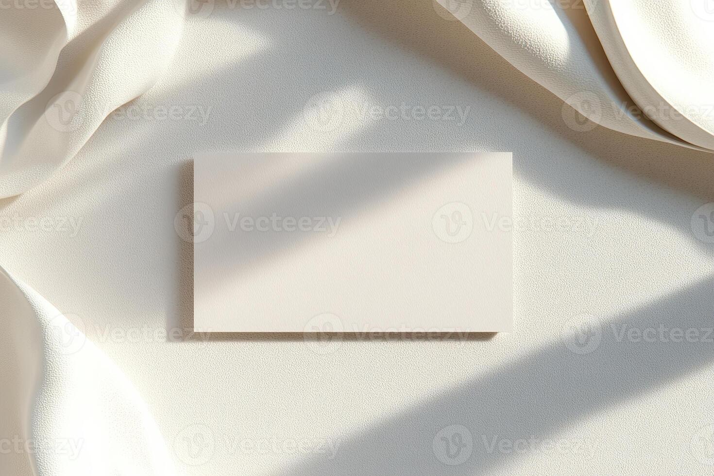 A blank business card rests flat on a smooth white surface, illuminated by soft natural light photo