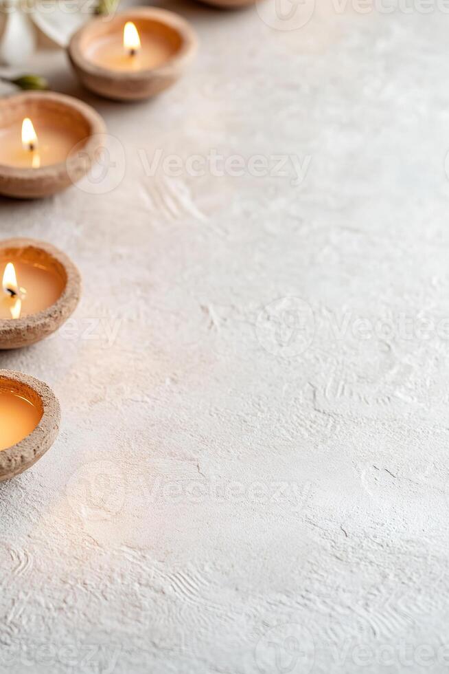 Beautifully detailed diyas cast a warm golden glow along the bottom border, complementing intricate Rangoli patterns against a neutral backdrop, perfect for festive occasions photo
