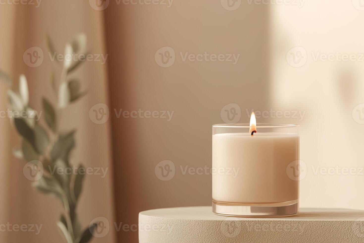 A warm amber candle glows gently, casting soft light in a dimly lit room. The blurred, neutral background enhances the inviting ambiance perfect for relaxation and home decor photo
