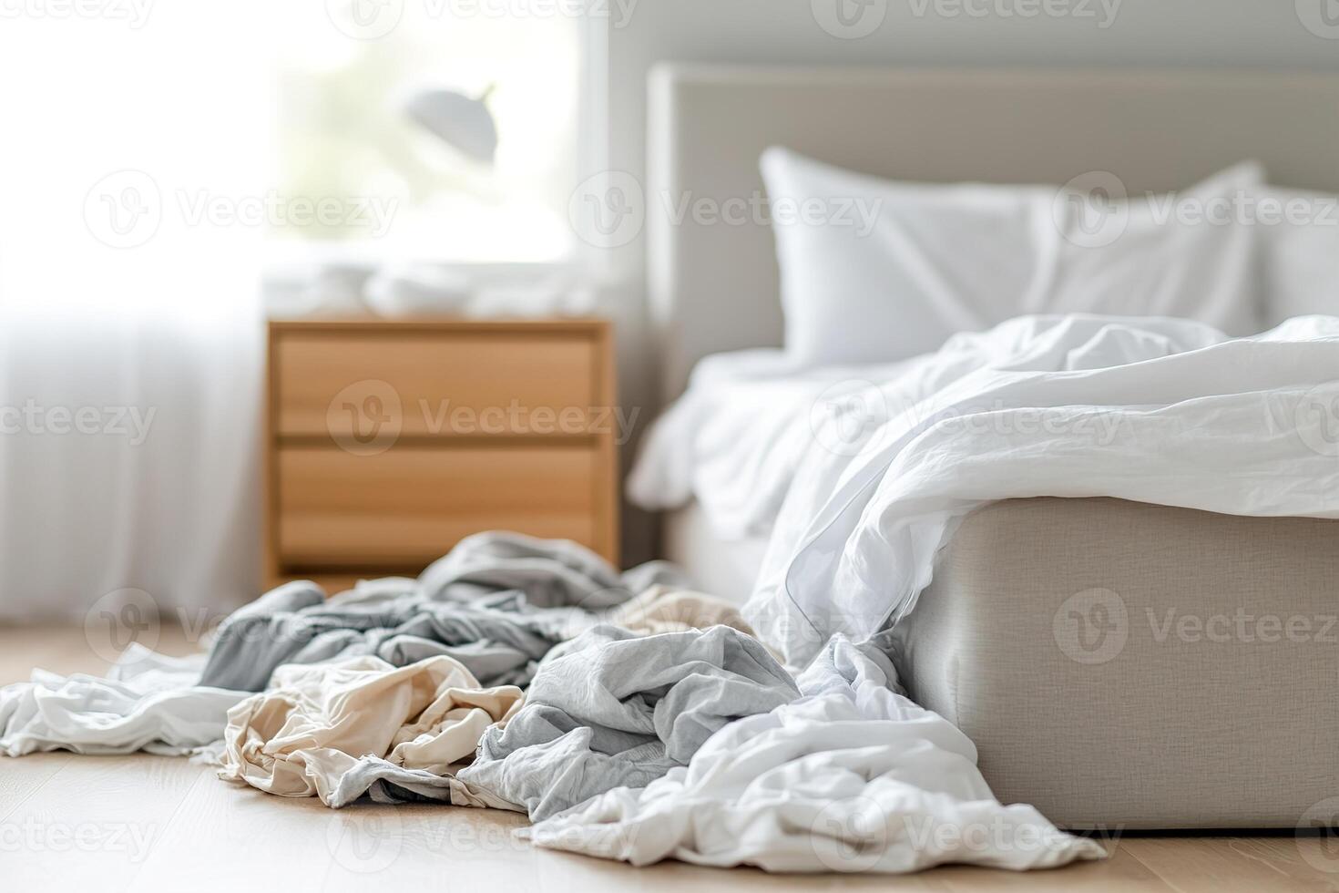 Clutter fills the bedroom space, with an unmade bed and clothes thrown on the floor. Soft natural light filters through the curtains, emphasizing the need for tidiness and organization photo