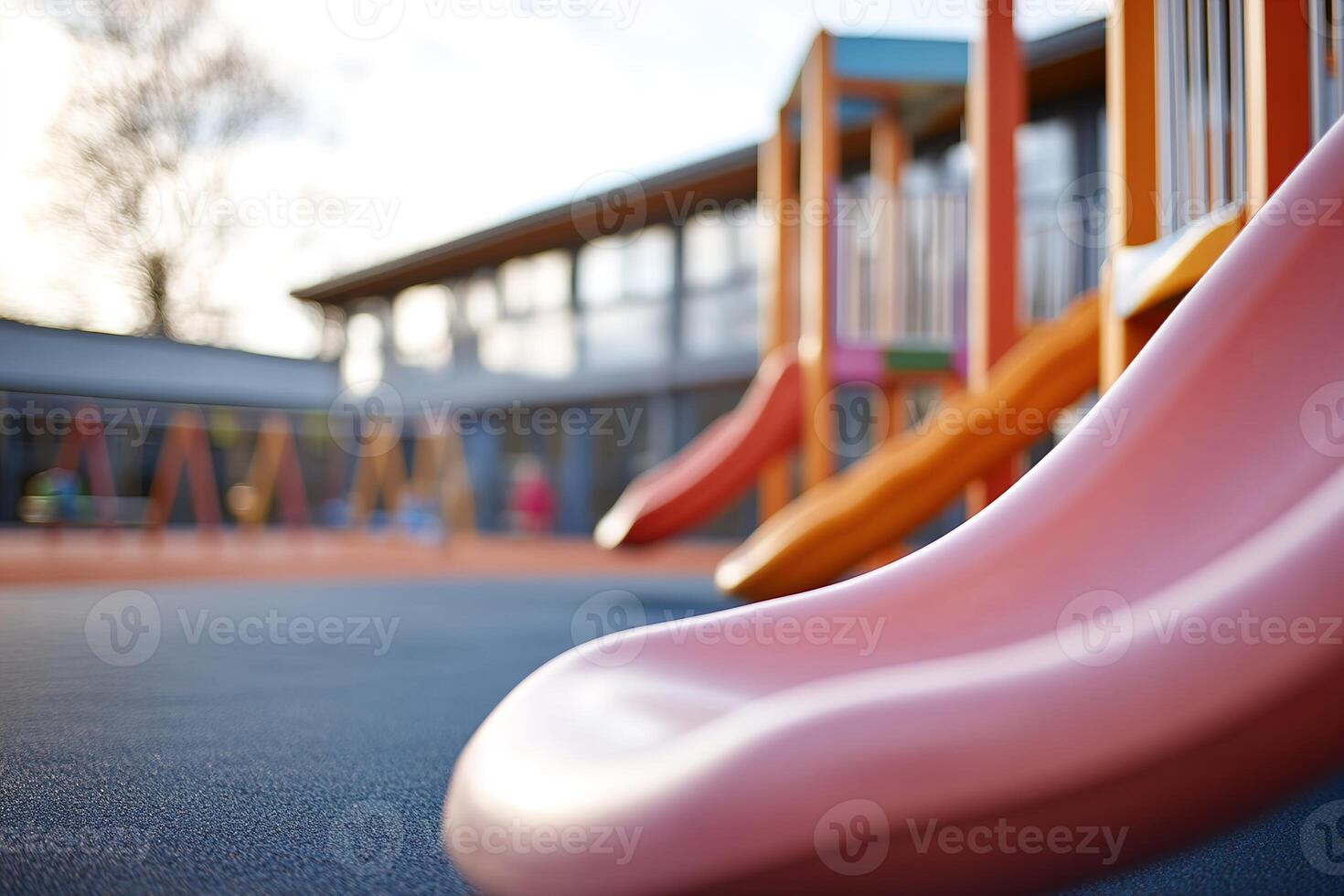 Bright slides and swings invite children to play in a lively playground. In the background, kids can be seen enjoying themselves under a clear sky, creating a joyful atmosphere photo