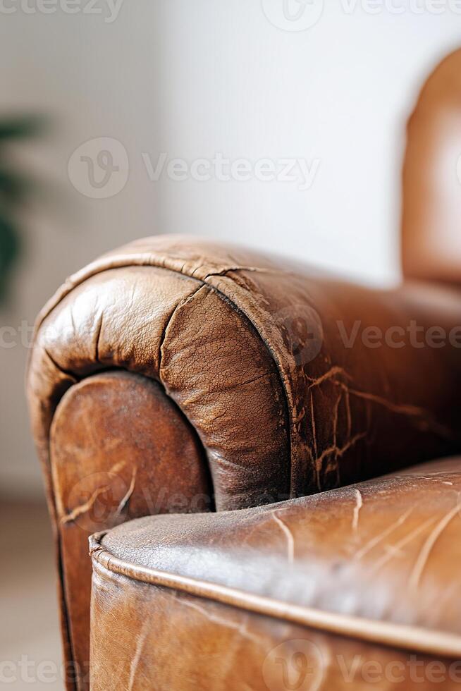 Dust lightly coats this vintage leather armchair, highlighting its cracks and wear. Soft focus background contributes to a rustic ambiance suitable for restoration and cleaning photo