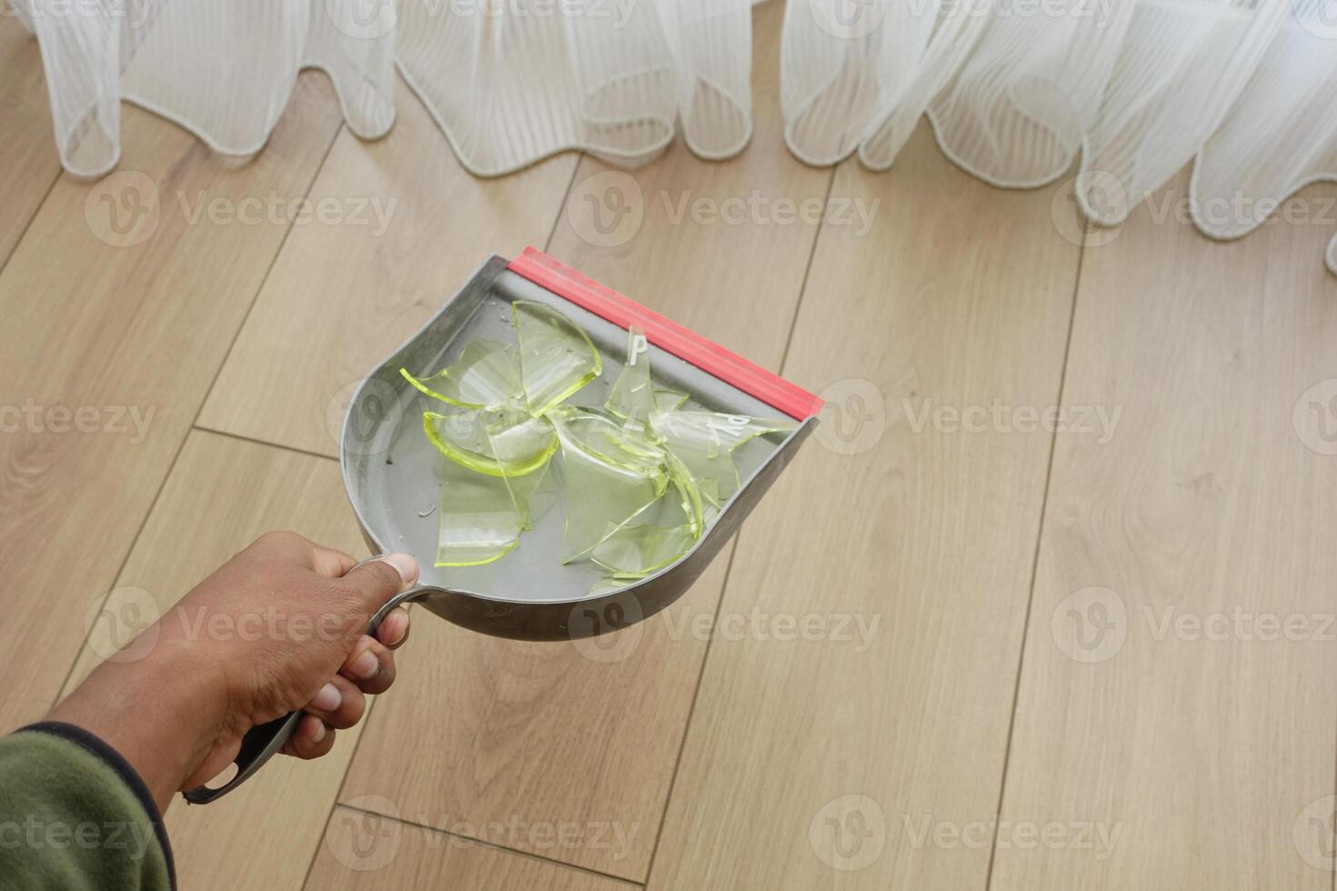 Cleaning up broken glass with a dustpan in a bright room photo