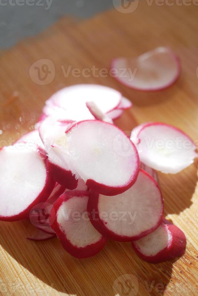 Freshly sliced radishes on a wooden cutting board in natural light photo