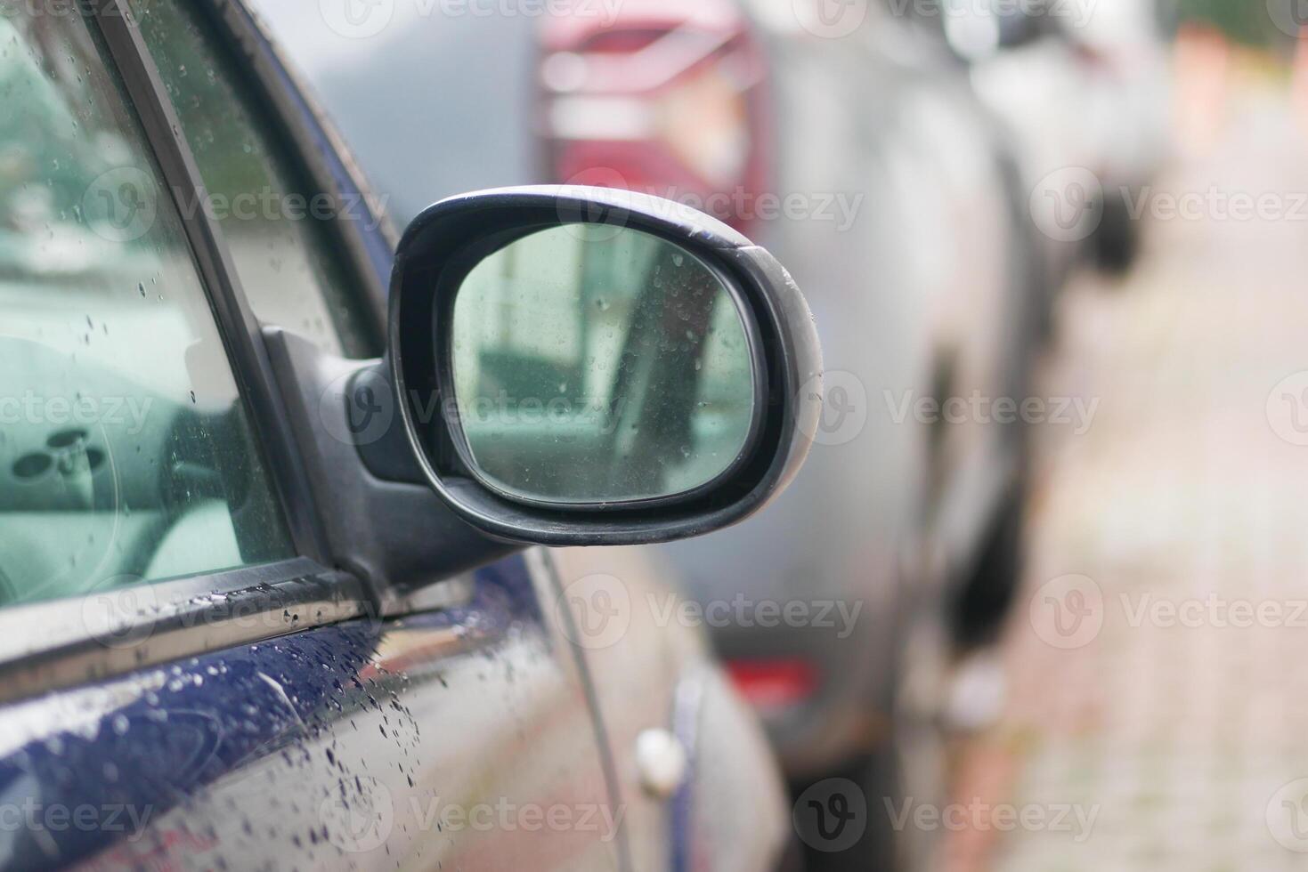 Car side mirror reflects cloudy sky and parked vehicles photo