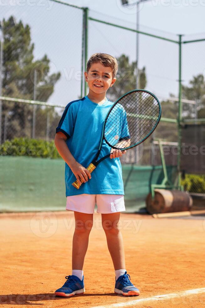 Little boy playing tennis on a dirt court photo