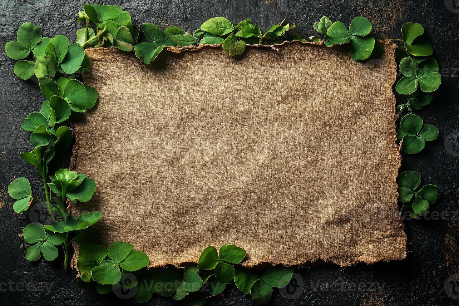 Green clovers frame an old empty paper sheet on a dark background, providing copy space for saint patrick's day greetings photo