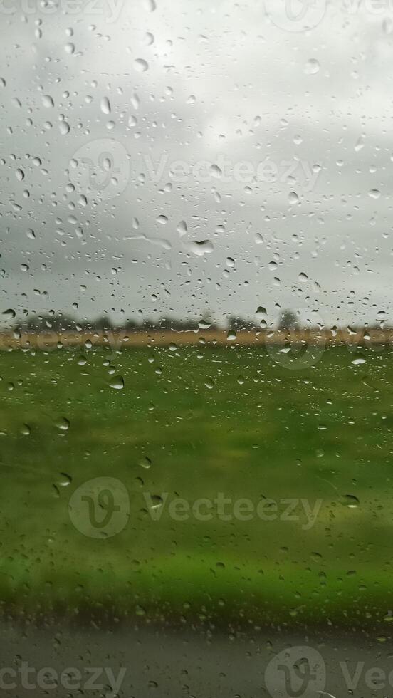 Raindrops flowing on glass surface during rainy day in czech republic countryside photo