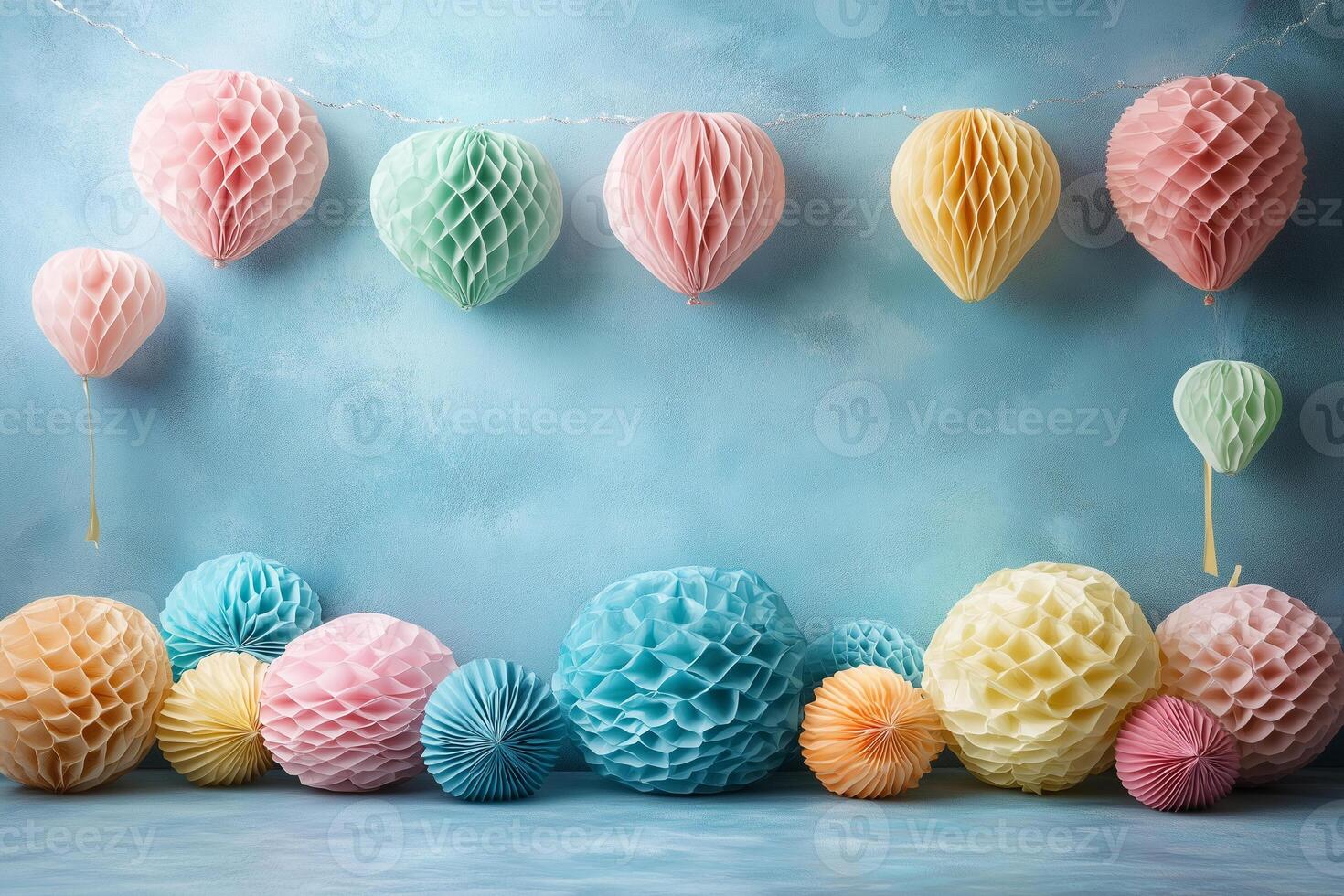 Pastel paper decorations dangling from string, lying on light blue surface, cheerful party or carnival mood copy space photo