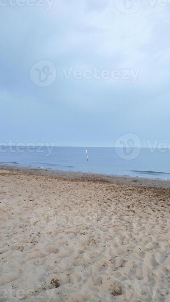 Bibione coastline stretching across sandy shore, merging turquoise waters with soft summer twilight under expansive azure sky photo