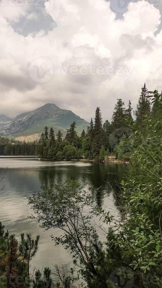 Strbske pleso lake reflecting majestic mountain under cloudy sky in high tatras, slovakia photo