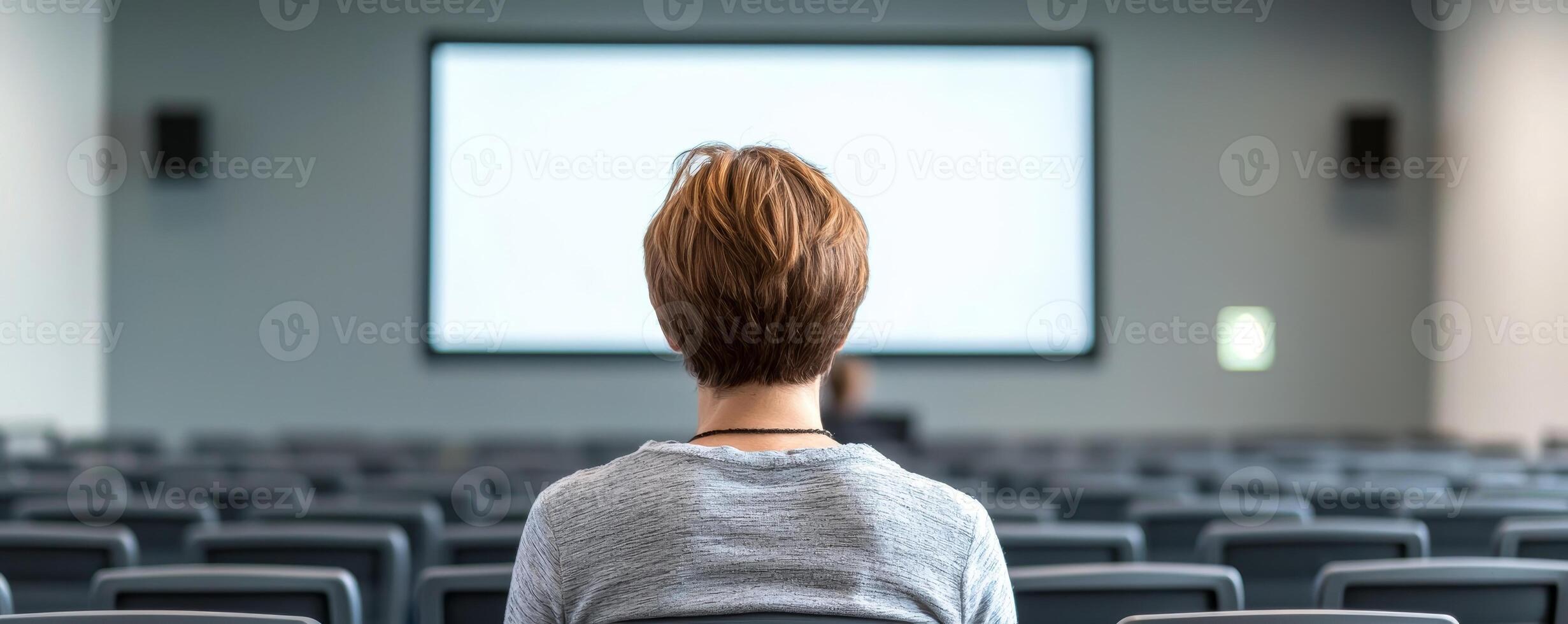 Digital transformation e-learning courses concept. A person seated in a conference room facing a large screen with empty chairs around. photo