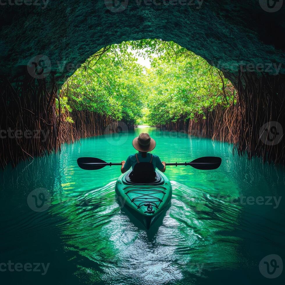 Exploring nature hidden gem concept. A person kayaking through a lush, green tunnel of trees over clear water. photo
