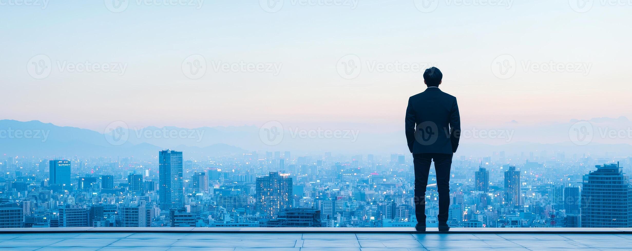 Inspirational success story motivation concept. A man stands overlooking a city skyline at dusk, reflecting on the view before him. photo