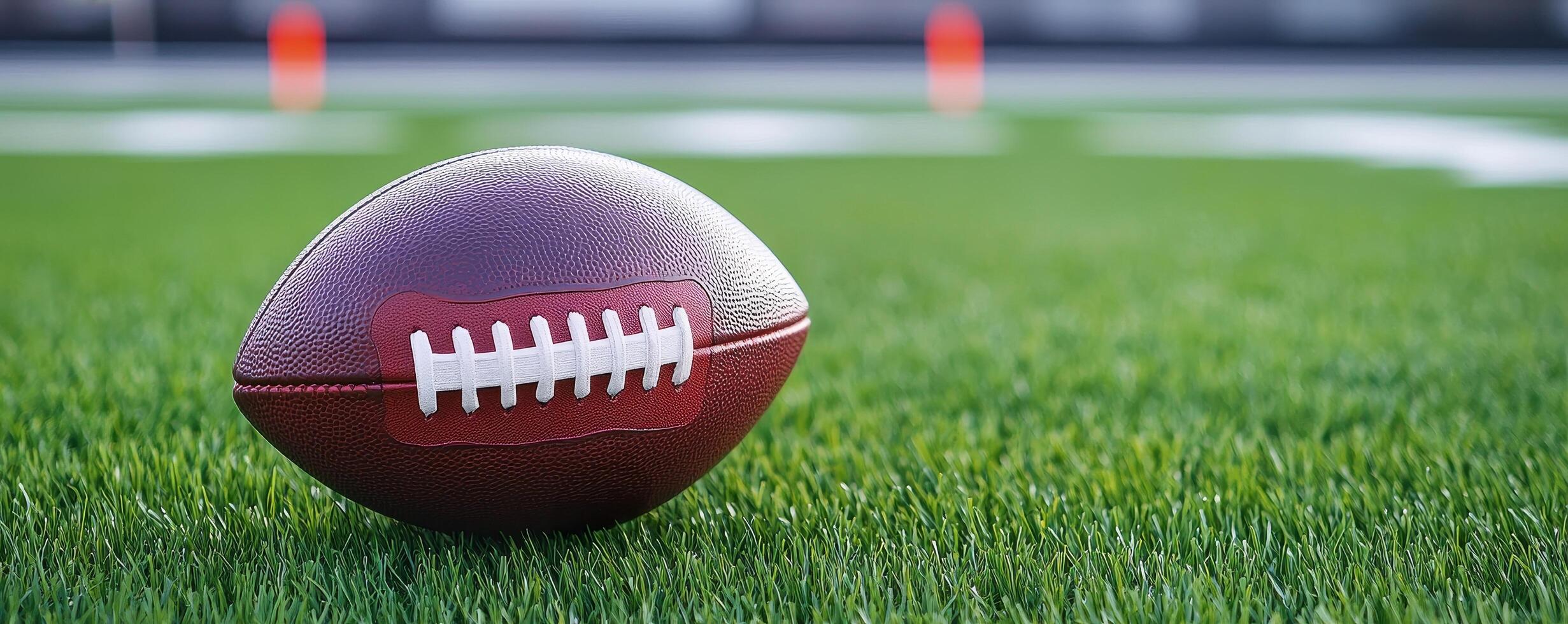 A close-up of a football resting on vibrant green grass, highlighting its textured surface and stitching against a blurred field background. photo