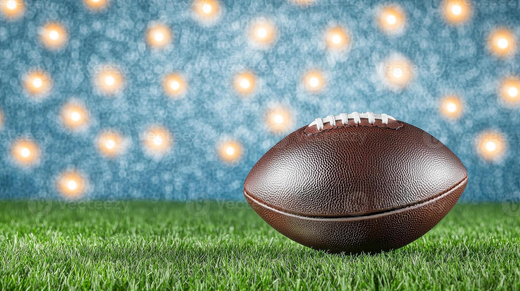 A brown football resting on lush green grass, with a soft, blurred background featuring bright lights, creating a vibrant sports atmosphere. photo